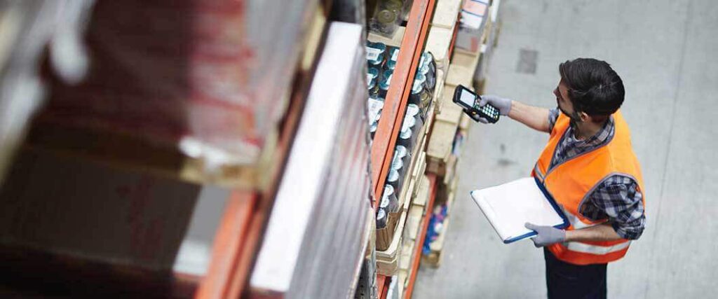 A warehouse workers scanning a barcode on some items located on a shelf