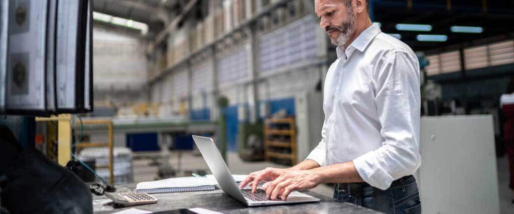A warehouse manager entering data via a laptop